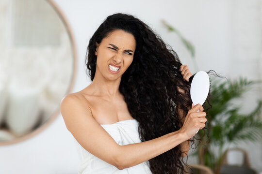 mulher tentando pentear o cabelo ressecado